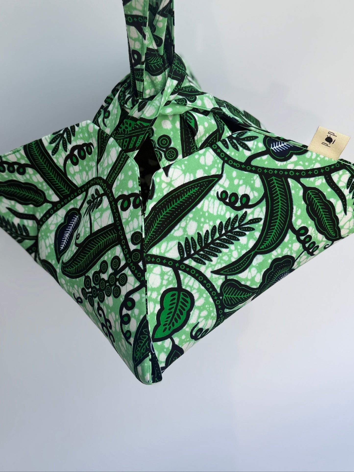 Green and black patterned bag with a visible brand label on a white background